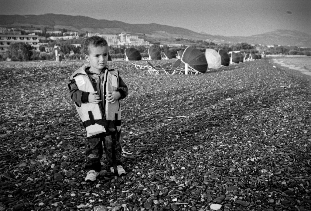 A refugee child still wears his life vest after safely reaching the beach of Kos, Greece. Photo courtesy of Okke Ornstein