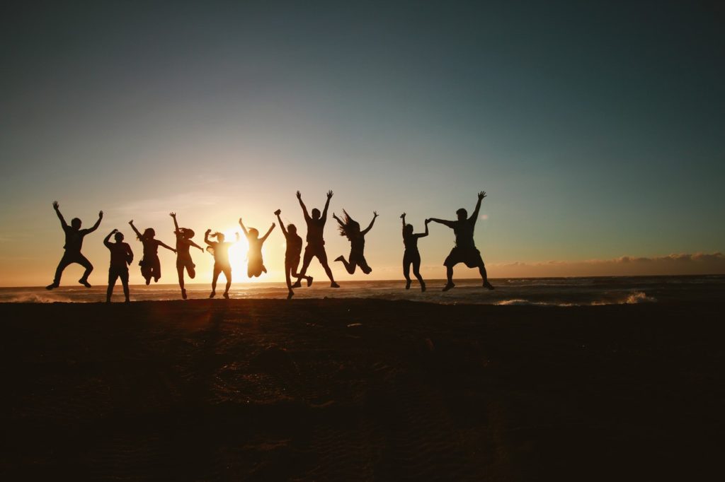 Silhouette of happy people jumping on a beach.